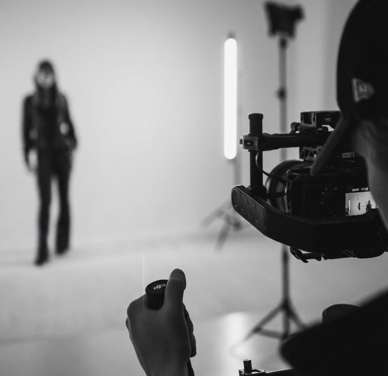 An operator on a gimbal rig filming a model walking the white cyc wall
